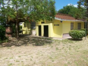 a small yellow house with a tree in the yard at Casa Bichi in Villa Gesell