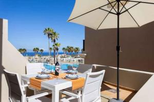 a white dining table with chairs and an umbrella at Apartment in Palm Mar - Insel Teneriffa 53099 in Palm-mar