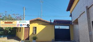 ein gelbes Haus mit einem Schild davor in der Unterkunft Cabo Frio - Hospedagem Central - Aluguel Econômico in Cabo Frio