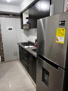 une cuisine avec un réfrigérateur en acier inoxydable et des armoires noires dans l'établissement Apartamento amplio en conjunto, à Ibagué