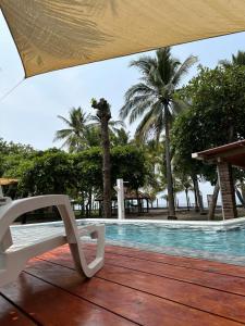 una sedia bianca seduta su una terrazza in legno accanto alla piscina di Sihua Escape a Teotepeque