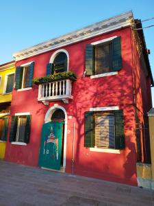 a red building with a green door and a balcony at Casa degli Artisti in Burano