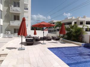 a patio with umbrellas and chairs and a pool at Boca del Mar III, apto 707 in Boca Chica