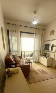 uma sala de estar com um sofá e uma janela grande em Apartamento Enseada no Guarujá