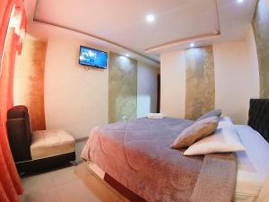 a bedroom with a bed and a tv on the wall at Hostal Dugan in Baños +40 photos
