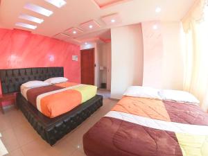 two beds in a room with a red wall at Hostal Dugan in Baños