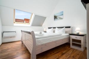 a white bedroom with a bed and a window at Fischerhaus-307-am-Yachthafen-Rechlin-Nord in Rechlin