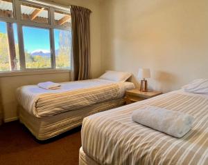 two beds in a room with a window at Matagouri Cottage - Lake Tekapo in Lake Tekapo