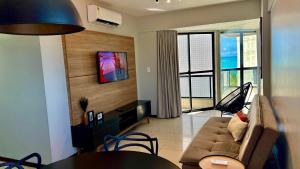 un salon avec un canapé, une table et une télévision dans l'établissement Casabela 405 | Beira mar de Pajuçara | 2 quartos, à Maceió