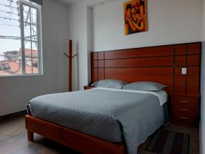 a bedroom with a bed with a wooden headboard and a window at HOTEL DEL RIVER MONUMENTO in Sangolquí