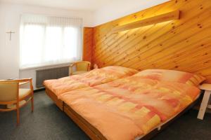 a bedroom with a large bed and a wooden wall at Allegro Alpin Lodge in Einsiedeln