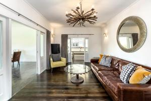 a living room with a brown couch and a mirror at The Cattlestop in Martinborough 