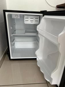 un réfrigérateur vide avec sa porte ouverte dans une cuisine dans l'établissement Hospedagem 20m da praia., à Itapema