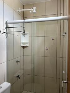 une douche avec une porte vitrée dans une salle de bain dans l'établissement Hospedagem 20m da praia., à Itapema