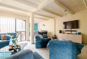 a living room with blue couches and a tv at Casa Hermosa in Quito