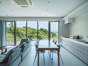 kuchnia i salon ze stołem i krzesłami w obiekcie Blue Rela Luxe Resort Okinawa w mieście Onna
