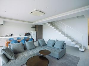 salon z kanapą, stołem i schodami w obiekcie Blue Rela Luxe Resort Okinawa w mieście Onna