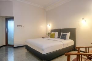ジョグジャカルタにあるUrbanview Omah Pari Boutique Hotelの白いシーツと枕が付いた大きなベッドのある寝室 +65枚の写真