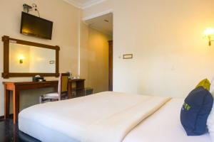 ジョグジャカルタにあるUrbanview Omah Pari Boutique Hotelのベッドと机と鏡のある寝室