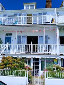 a white house with a balcony with red and white flags at Beachfront Studio Apartment in Felixstowe
