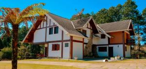a white and orange house with a tree at Recanto Lucerna in Campos do Jordão