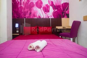 un gatto giace su un letto rosa di Bies Malioboro Hotel RedPartner a Yogyakarta