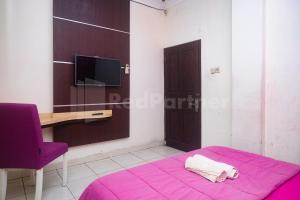 Camera con letto viola, scrivania e TV. di Bies Malioboro Hotel RedPartner a Yogyakarta Altre 25 foto