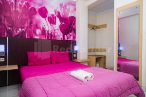 una camera con un letto rosa e un asciugamano sopra di Bies Malioboro Hotel RedPartner a Yogyakarta