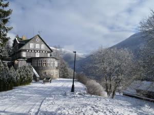 ein großes Gebäude im Schnee mit einer Stange in der Unterkunft Hotel Panorama in Špindlerův Mlýn