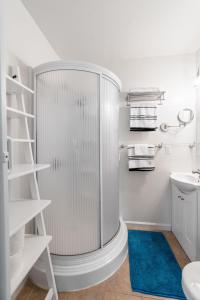 a white bathroom with a shower and a blue rug at The Berkeley Haven in Berkeley +15 photos