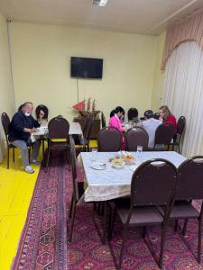 Un grupo de personas sentadas en mesas en una habitación. en Bukhara house hotel, en Bukhara