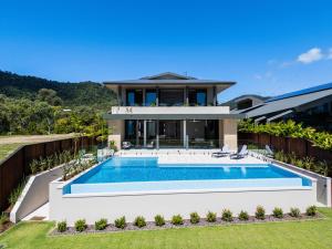 a villa with a swimming pool in front of a house at Jasper in Airlie Beach