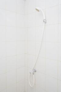 a white tiled shower with a shower head at Fully Furnished with Cozy Design Studio Poris 88 Apartment By Travelio in Tangerang +8 photos