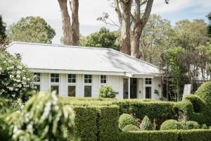 an old white house with bushes and trees at The Merribee in Numba