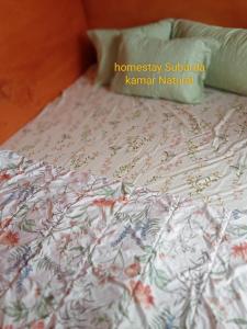 a close up of a bed with a floral bedspread at Homestay Subarda Kamar Natural in Solok