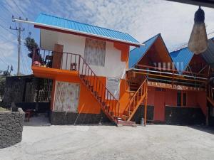 an orange and white house with a blue roof at Homestay Subarda Kamar Natural in Solok