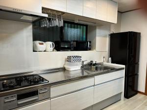 a kitchen with a sink and a black refrigerator at Umikaji Base WAKASA in Naha