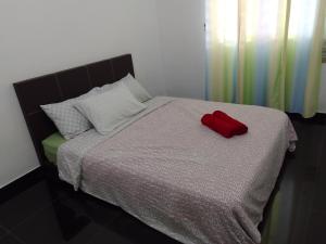 cuscino rosso posto sopra un letto di Islam Taqwa Homestay a Kuala Lipis