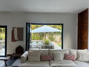 a living room with a white couch and an umbrella at Blue Palm Villa with Private Pool & Tropical Garden in Cap Malheureux