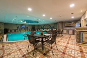 a pool room with a table and chairs next to a pool at Akar International Hotel in Ankara