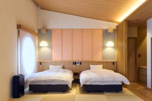 a bedroom with two beds and a window at ICHIFUJI Ryokan in Hitoyoshi