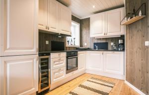 Una cocina con gabinetes blancos y electrodomésticos negros. en Stunning Home In Rauland With Wifi, en Rauland