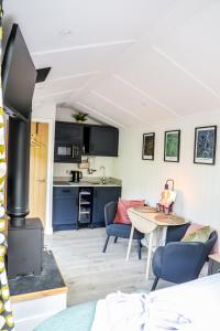 a living room with a table and a kitchen at Ty Nant Gwenyn in Llanymawddwy