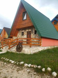 a cabin with a green roof and a stone wall at Holiday Home Vojinovic in Žabljak