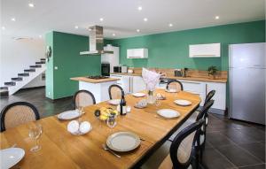 a wooden table with chairs and a kitchen with green walls at Nice Home In Suze-La-Rousse With Wifi in Suze-la-Rousse