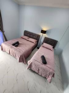 two beds in a room with pink sheets and pillows at Roomstay McAyoh Self Check In Concept in Setiu