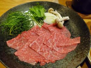 a plate of meat and vegetables on a table at Itoya Ryokan in Nanyo