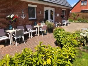 a patio with tables and chairs in front of a brick building at Wattlöwe ruhige Ferienwohnung mit Terrasse nahe Eider & Deich in Tönning