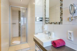 a white bathroom with a sink and a shower at Wellnesshotel Waldruh in Bad Kohlgrub +66 photos