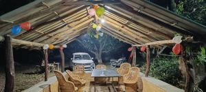 a table and chairs under a wooden pergola at Corbett Green Orchard in Rāmnagar